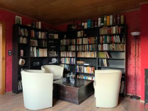 een bibliotheek met twee witte stoelen en een tafel en boeken bij Ferienhaus Liebchen free Netflix in Freienhagen