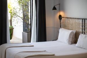 una camera da letto con un letto con lenzuola bianche e una finestra di 7 Islas Hotel a Madrid