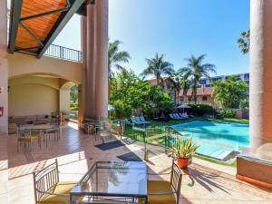 een patio met een zwembad en tafels en stoelen bij Mercure Hotel Nelspruit in Nelspruit