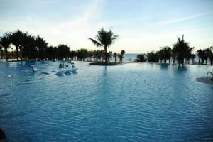 uma grande piscina de água com cisnes numa praia em ARTRA resort- near Cam Ranh Airport em Cam Ranh