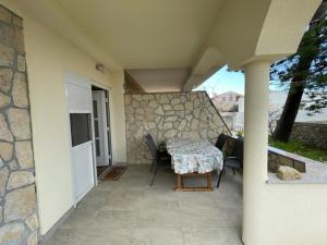 eine Terrasse mit einem Tisch, Stühlen und einer Steinmauer in der Unterkunft Apartman Stela in Nin