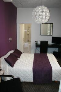 a bedroom with a large bed and a chandelier at Hôtel Le Chambellan in Dijon