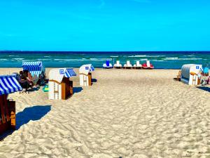 einen Strand mit blauen und weißen Sonnenschirmen und Stühlen in der Unterkunft Modernes Apartment an Timmendorfer Promenade, 1. Reihe in Timmendorfer Strand