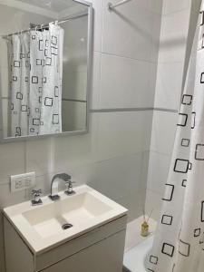 Baño blanco con lavabo y espejo en 5-Súper Dpto en Morón centro, en Morón