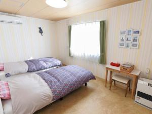 a bedroom with a bed and a table and a window at Pension Ken&Mary in Biei