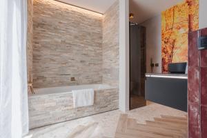 a bathroom with a tub and a stone wall at BEE n BEE in Bruges