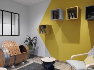 un salon avec un mur jaune, une chaise et des livres dans l'établissement Gîte indépendant avec SPA, jardin, terrain de pétanque, proche vignoble du Champagne à Colombey - FR-1-611-45, à Colombey-les-Deux-Églises