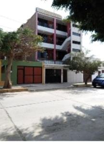 a parking lot in front of a building with a parking garage at Hostal Iberia in Talara