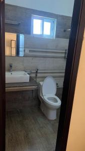 a bathroom with a toilet and a sink and a window at 62hills hotel ayubia in Ayubia