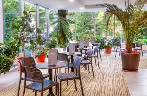 un restaurante con mesas, sillas y plantas en Hunguest Hotel Gyula, en Gyula