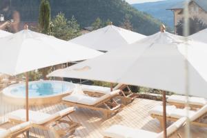 un grupo de sillas y sombrillas junto a una piscina en Schgaguler Hotel, en Castelrotto