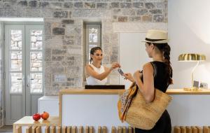 a woman standing in front of a mirror brushing her hair at Trapela Limeni Luxury Suites in Limeni