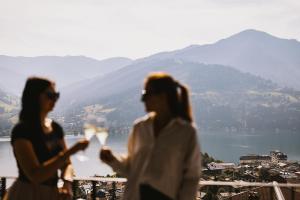 zwei Frauen stehen auf einem Balkon und trinken Wein in der Unterkunft Nikolaus by AvenidA Panoramic Wellness Suites in Zell am See