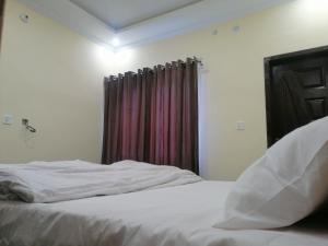 a bedroom with a white bed with a window at Navid's Holiday Resort and Hotel, Murree in Ghora Gali