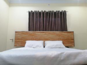 a bed with two white pillows in front of a curtain at Navid's Holiday Resort and Hotel, Murree in Ghora Gali