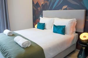 - une chambre avec 2 lits dotés d'oreillers bleus dans l'établissement Guest House Jacarandá Faro, à Faro