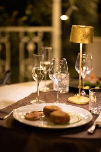 uma mesa com um prato de comida e copos de vinho em Alla Corte Delle Terme Resort em Viterbo