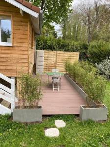 a wooden deck with a table and chairs in a yard at Au Bord de l'Oise in Auvers-sur-Oise