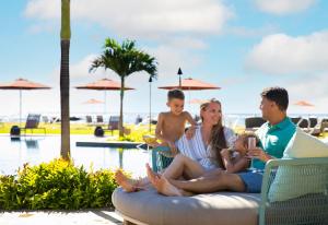 een gezin op een strandstoel naast een zwembad bij Sheraton Kauai Coconut Beach Resort in Kapaa