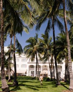 kobieta przechodząca przez palmy przed budynkiem w obiekcie The Betsy Hotel, South Beach w Miami Beach