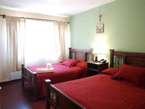 1 Schlafzimmer mit 2 Betten mit roter Bettwäsche und einem Fenster in der Unterkunft Hotel Maison Fiori Prado in Cochabamba