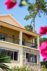 una casa con balcón y flores rosas delante de ella en Moby Dick Lodge Colares, en Colares