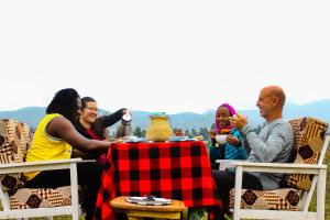 un groupe de personnes assises à une table dans l'établissement Under Volcanoes View Guest House, à Nyarugina