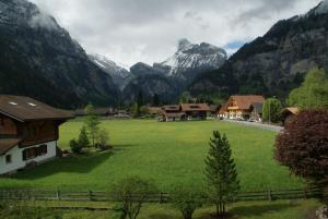 un grande campo verde con montagne sullo sfondo di Hotel Pension Spycher a Kandersteg