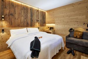 um quarto com uma cama branca e uma cadeira em Hotel Garni dello Sportivo em Madonna di Campiglio