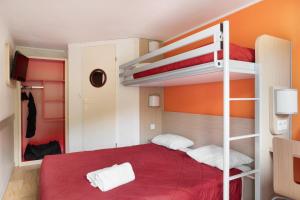 een slaapkamer met 2 stapelbedden en een rood bed bij Premiere Classe La Ville Du Bois in La Ville-du-Bois