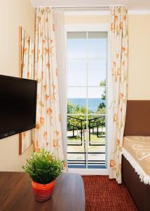 a bedroom with a large window and a television at Dom Wczasowy Plaża in Rewal