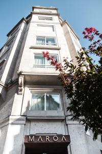 Un alto edificio bianco con un cartello bordeaux. di Hotel Maroa Vigo a Vigo