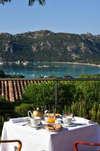 uma mesa com um conjunto de chá sobre ele, com vista para a água em Hôtel Alivi Di Santa Giulia em Porto-Vecchio