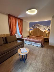 ein Hotelzimmer mit einem Bett, einem Sofa und einem Tisch in der Unterkunft Hotel Des Glaciers in Courmayeur