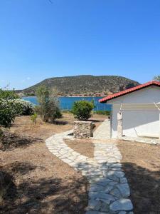 拉夫蒂港Coast Cottage Porto Rafti-Avlaki的水景石制走道,毗邻一座建筑