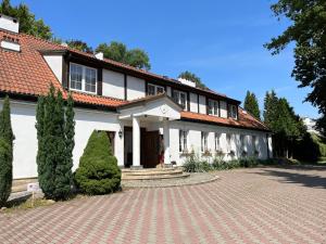 Uma casa branca com uma entrada de tijolos à frente. em Dedek Park - historyczny dworek w pięknym Parku Skaryszewskim obok Stadionu Narodowego em Varósvia