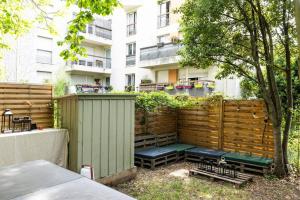 uma cerca de privacidade de madeira com um banco em frente a um edifício em Charmant Appartement avec Jardin em Suresnes