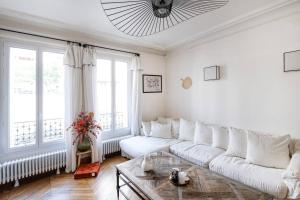 uma sala de estar branca com um sofá e uma mesa em Charmant Appartement avec Jardin em Suresnes