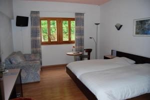 um quarto com uma cama, uma cadeira e uma janela em Hotel du Pigne em Arolla