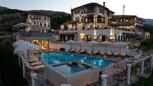 un hôtel avec une piscine en face d'un bâtiment dans l'établissement KERCULLA Resort, à Gjirokastër