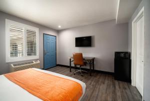 Schlafzimmer mit einem Bett, einem Schreibtisch und einem TV in der Unterkunft LYFE INN & SUITES by AGA - LAX Airport in Inglewood