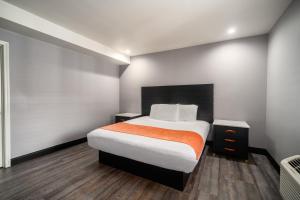 ein Schlafzimmer mit einem großen Bett mit einer orangefarbenen Decke in der Unterkunft LYFE INN & SUITES by AGA - LAX Airport in Inglewood