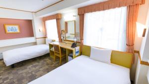 ein Hotelzimmer mit 2 Betten und einem Schreibtisch in der Unterkunft Toyoko Inn Hiroshima-eki Shinkansen-guchi 1 in Hiroshima