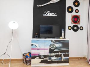 Zimmer mit einem TV und einer Wand mit einem Bild eines Autos in der Unterkunft Apartment MemLing-3 by Interhome in Vilafortuny