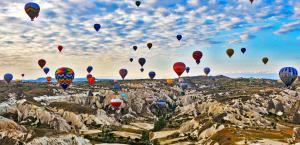 Ein Haufen Heißluftballons fliegt in den Himmel in der Unterkunft Ages in Cappadocia in Uchisar