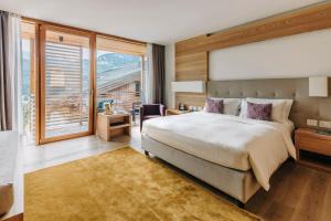 1 dormitorio con cama grande y ventana grande en Hotel Lajadira & Spa, en Cortina dʼAmpezzo