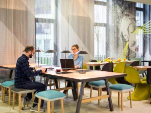 a man and a woman sitting at a table with a laptop at Aparthotel Adagio Köln City in Cologne