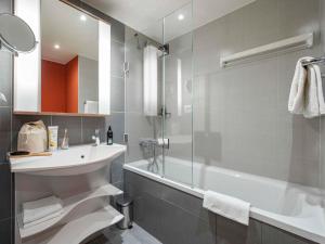 a bathroom with a tub and a sink and a shower at Aparthotel Adagio Köln City in Cologne