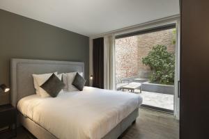 um quarto com uma cama grande e uma janela grande em Dukes' Apartments Grand Place - by Dukes' Hotel Collection em Bruges