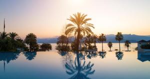 - une piscine avec des palmiers et le coucher du soleil dans l'établissement Akra Antalya, à Antalya